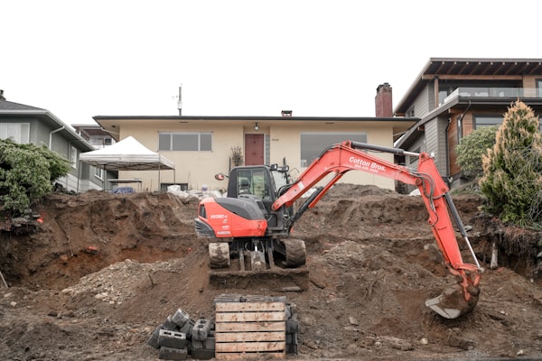 Excavator digging for septic system installation at a residential property